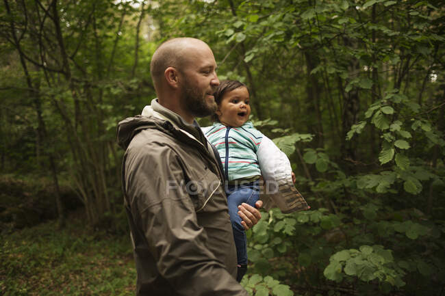 Uomo che tiene in braccio sua figlia mentre cammina nella foresta — Foto stock