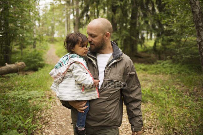 Homem segurando sua filha enquanto caminhava na floresta — Fotografia de Stock