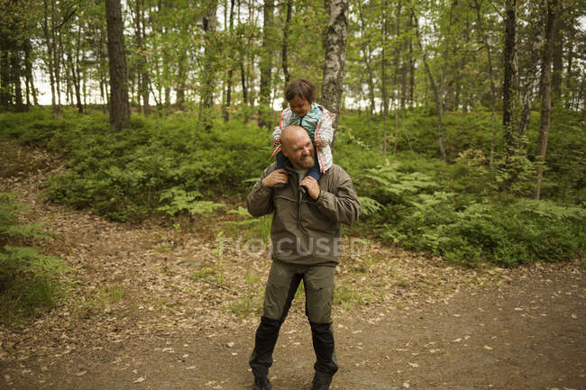 Man giving daughter piggyback ride while hiking — Stock Photo