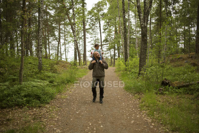 Мужчина катает дочь на спине во время похода — стоковое фото