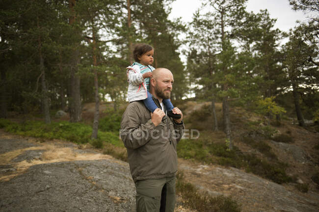 Hombre dando hija paseo a cuestas mientras caminata - foto de stock