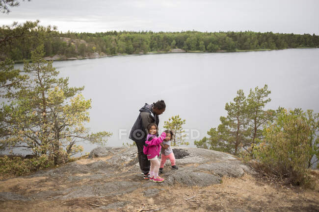 Жінка біля озера з дочками під час пішохідного туризму — стокове фото