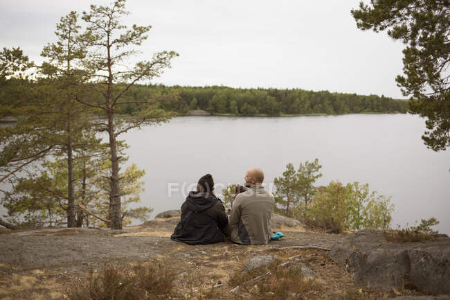 Семья, сидящая у озера во время похода — стоковое фото
