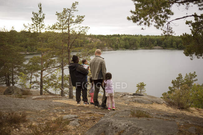 Family standing by lake while hiking — Stock Photo