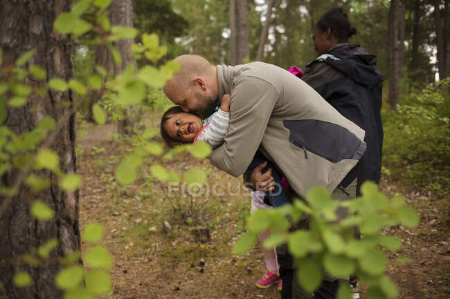 Hombre abrazando hija mientras senderismo en el bosque - foto de stock
