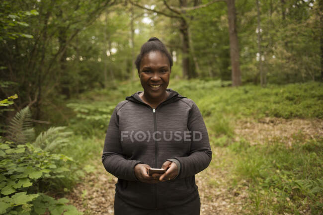 Mujer sonriente caminando en el bosque - foto de stock