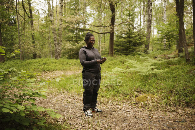 Mujer sonriente caminando en el bosque - foto de stock