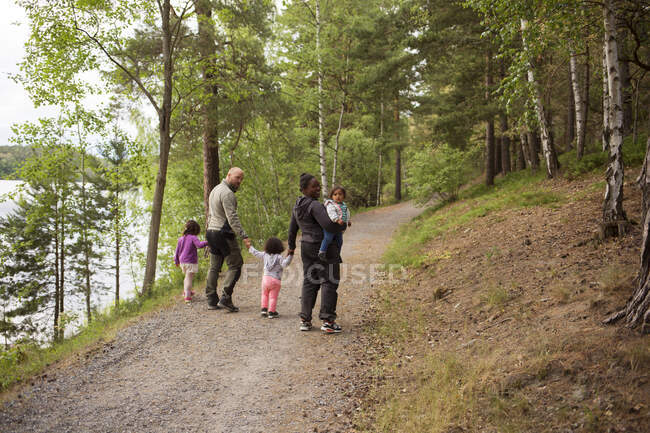 Family hiking on trail through forest — Stock Photo