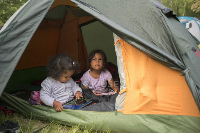 Сестры сидят в палатке во время кемпинга — стоковое фото