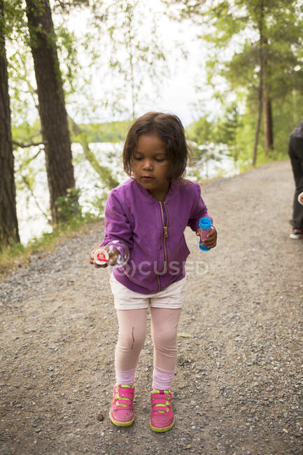 Menina brincando com varinha de bolha na floresta — Fotografia de Stock