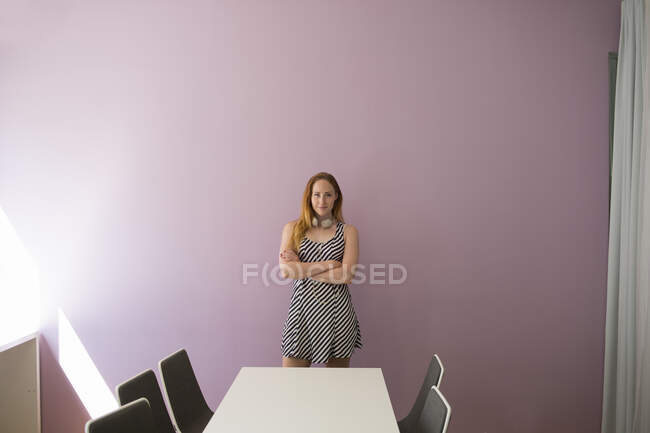 Jovem mulher em vestido listrado por mesa — Fotografia de Stock