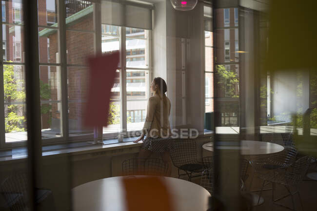 Молода жінка біля вікна в офісній перерві кімнаті — стокове фото