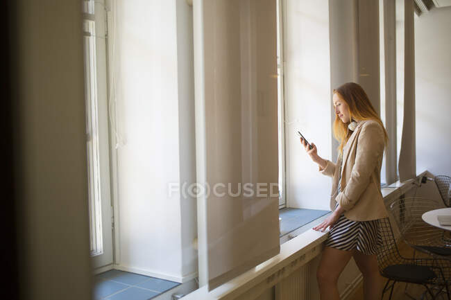 Jovem mulher por janela na sala de descanso do escritório — Fotografia de Stock