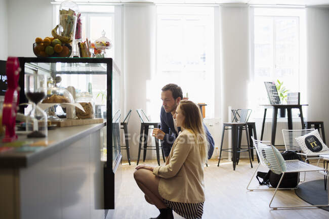 Young man and woman looking at display case on cafe — Stock Photo