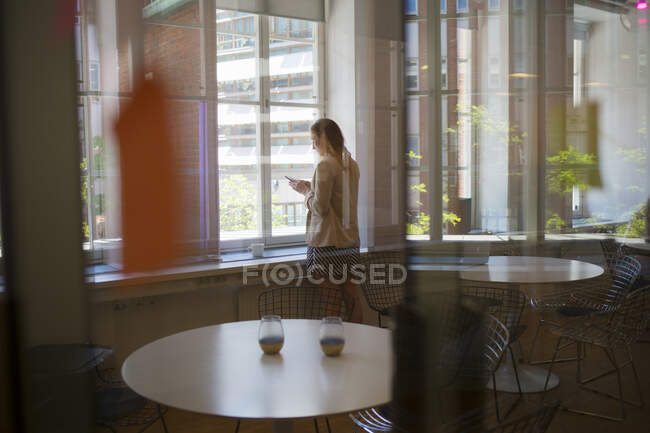 Jovem mulher por janela na sala de descanso do escritório — Fotografia de Stock