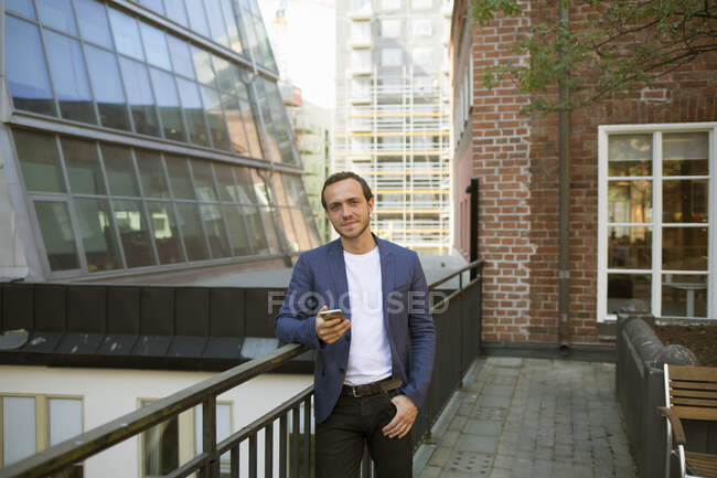 Homem de blazer apoiado no corrimão da varanda — Fotografia de Stock