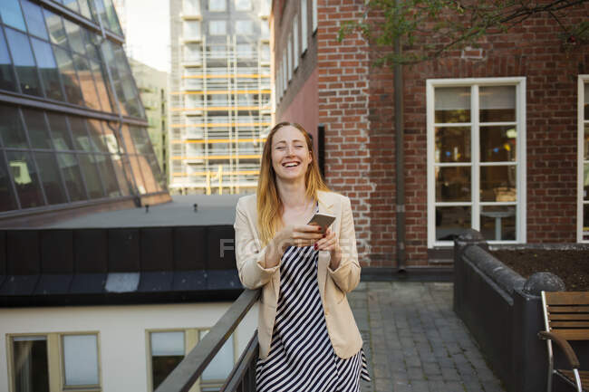 Giovane donna con smartphone sul balcone — Foto stock