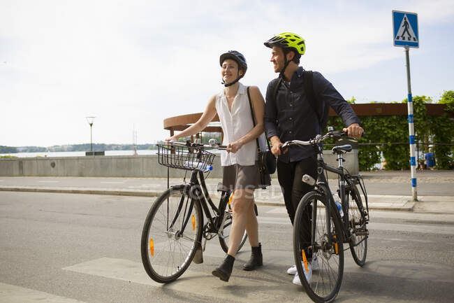 Jovem e mulher andando de bicicleta na rua da cidade — Fotografia de Stock