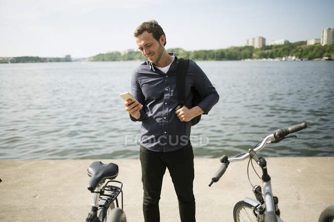 Молодой человек, стоящий у набережной на велосипеде — стоковое фото