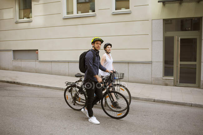 Young man and woman riding bicycles on city street — Stock Photo
