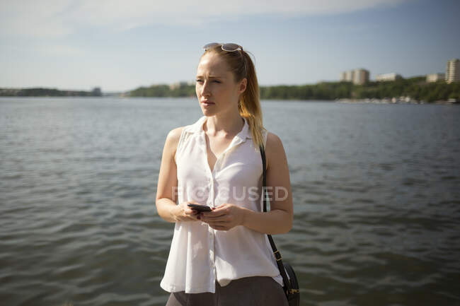 Молода жінка використовує смартфон на набережній — стокове фото