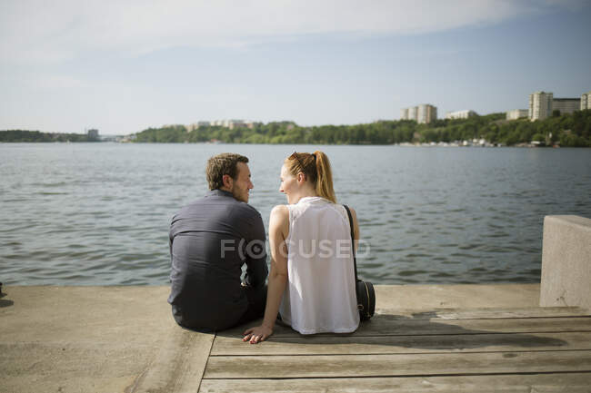 Couple sitting side by side at waterfront — Stock Photo