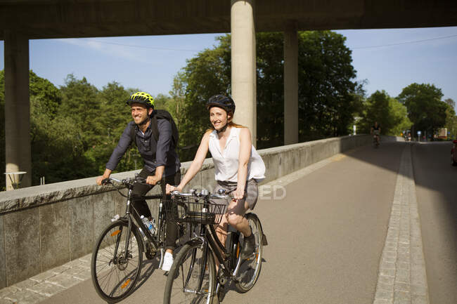 Hombre y mujer sonrientes montando bicicletas - foto de stock
