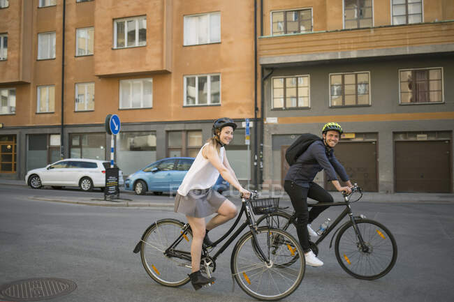 Молодой человек и женщина катаются на велосипедах по городской улице — стоковое фото