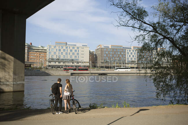 Young man and woman with bicycles on waterfront — Stock Photo
