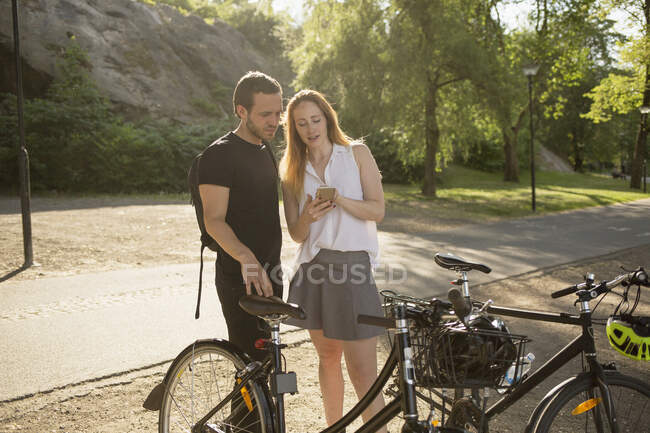 Молодой человек и женщина используют смартфон в парке — стоковое фото