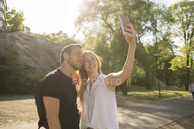 Couple taking selfie under sunshine in park — Stock Photo