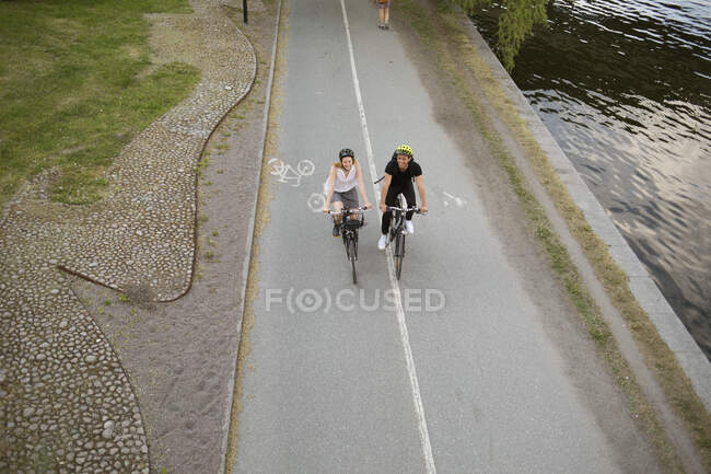 Joven hombre y mujer montando bicicletas en el parque - foto de stock