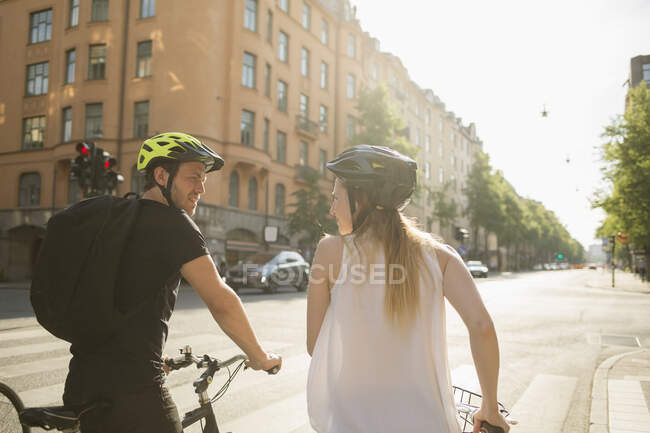 Young man and woman riding bicycles on city street — Stock Photo