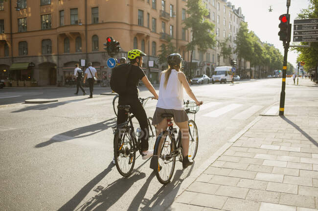 Молодой человек и женщина катаются на велосипедах по городской улице — стоковое фото
