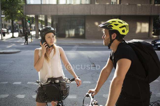Young man and woman with bicycles on city street — Stock Photo