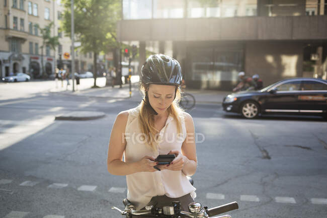 Jovem mulher na bicicleta usando smartphone — Fotografia de Stock