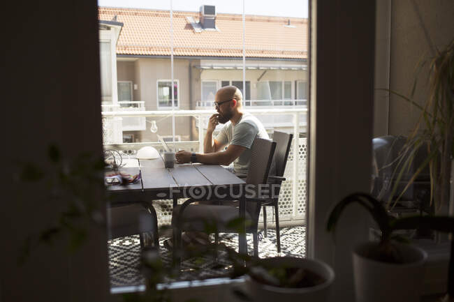 Человек, работающий из дома за обеденным столом — стоковое фото