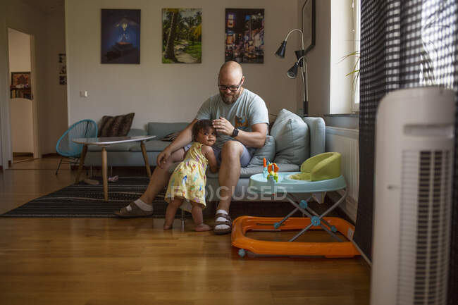Чоловік грає з дочкою у вітальні — стокове фото