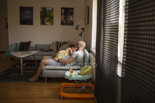 Uomo abbracciare sua figlia mentre seduto sul divano — Foto stock