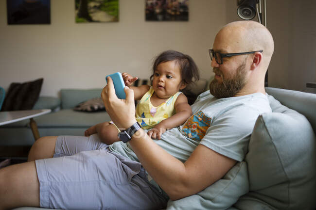 Мужчина показывает дочери свой смартфон — стоковое фото