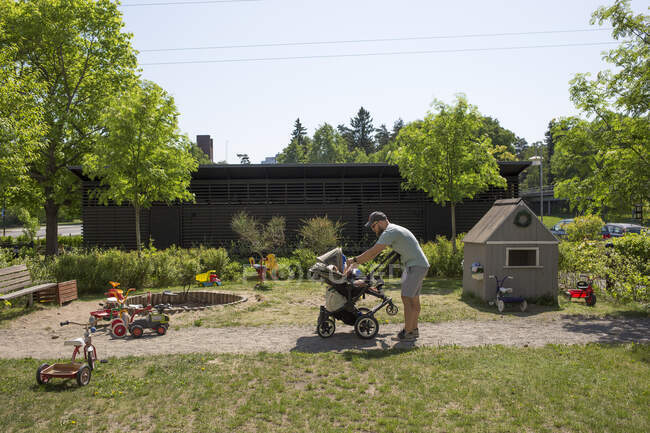 Мужчина с дочерью в коляске на заднем дворе — стоковое фото