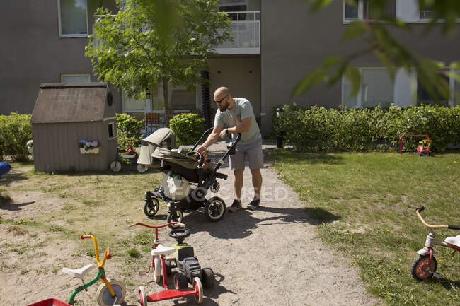 Мужчина с дочерью в коляске на заднем дворе — стоковое фото