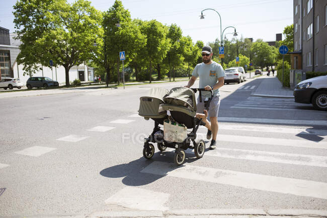 Homme marchant avec poussette dans la rue — Photo de stock