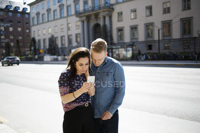 Woman showing man her smartphone on street — Stock Photo