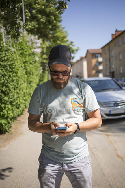 Uomo utilizzando smartphone sulla strada — Foto stock