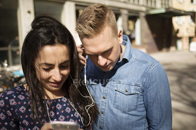 Жінка показує чоловікові свій смартфон на вулиці — стокове фото