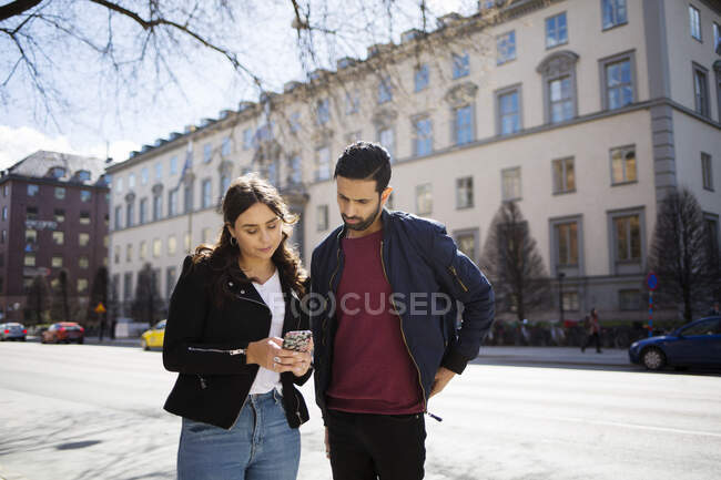 Mulher mostrando homem seu smartphone na rua — Fotografia de Stock