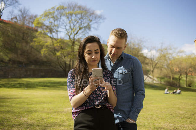 Frau zeigt Mann ihr Smartphone im Park — Stockfoto