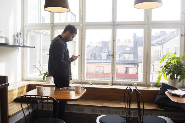 Молодий чоловік використовує смартфон в офісній перерві кімнаті — стокове фото
