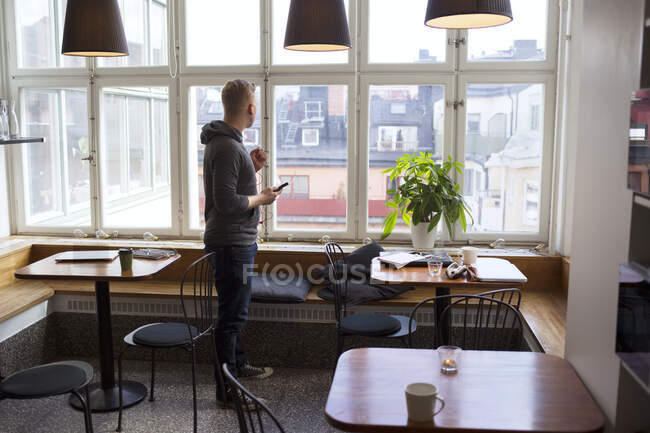 Young man with smartphone in office break room — Stock Photo